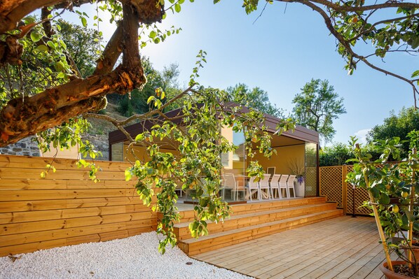Una terraza de madera con zona de estar y puerta de vidrio que da a un edificio.