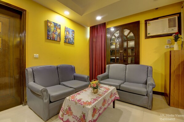 A living room with two grey sofas, a floral tablecloth, and a painting on the wall.