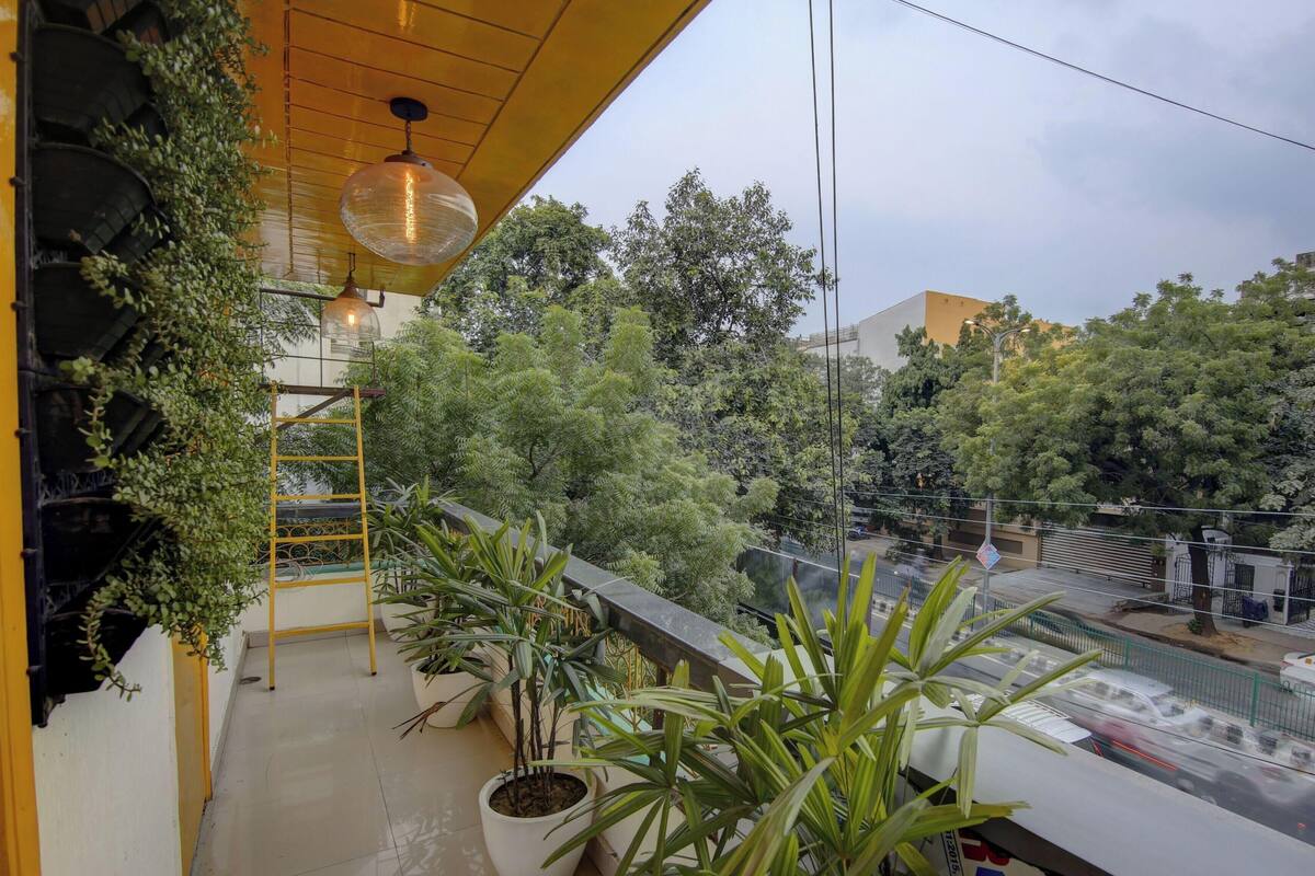 A balcony with potted plants, a hanging light fixture, and a view of a busy street.