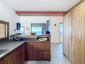 Una cocina moderna con una isla de madera, un ventanal y vista al mar.