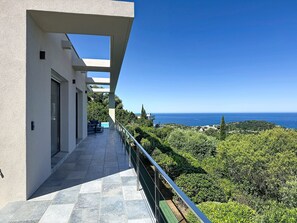 A modern building with a balcony overlooking a coastal landscape. - Stunning villa, sunset ocean view, heated pool, 4 bedrooms (Corbara)
