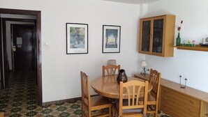 A dining area with a round table, wooden chairs, a cabinet, and two framed pictures on the wall.