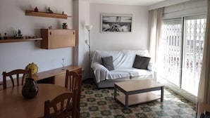 A living room with a sofa, a coffee table, a dining table with chairs, a cabinet, and a floor lamp.