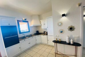 Cozinha compacta com armários brancos, bancada preta e uma pequena janela.