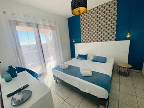 Quarto de hotel moderno com uma cama grande, uma escrivaninha e vista para o exterior.