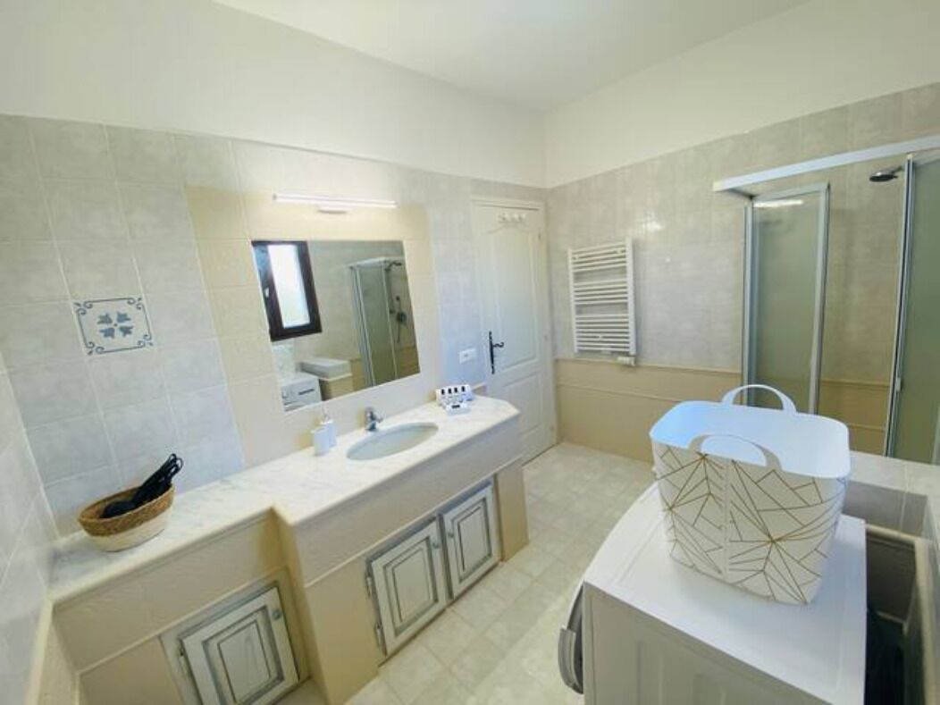 Une salle de bain moderne dotée d’un meuble-lavabo à deux vasques, d’un grand miroir, d’une zone de douche et d’un porte-serviettes.