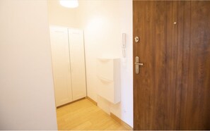 Enter a simple, well-appointed room with a wooden door, a wardrobe, and a wall-mounted telephone.