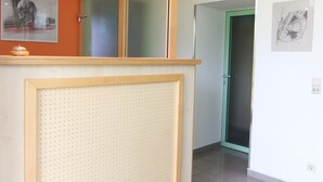 A reception area with a wooden reception desk, a green door, and a tiled floor. - Gästehaus am Lausitzring (Sallgast)