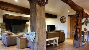 Een gezellige woonkamer met een stenen open haard, een grote bank en een houten salontafel.