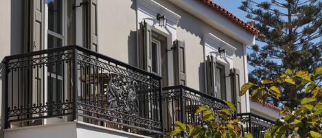 Un edificio con balcón, con barandillas de metal negro ornamentado y fachada blanca.
