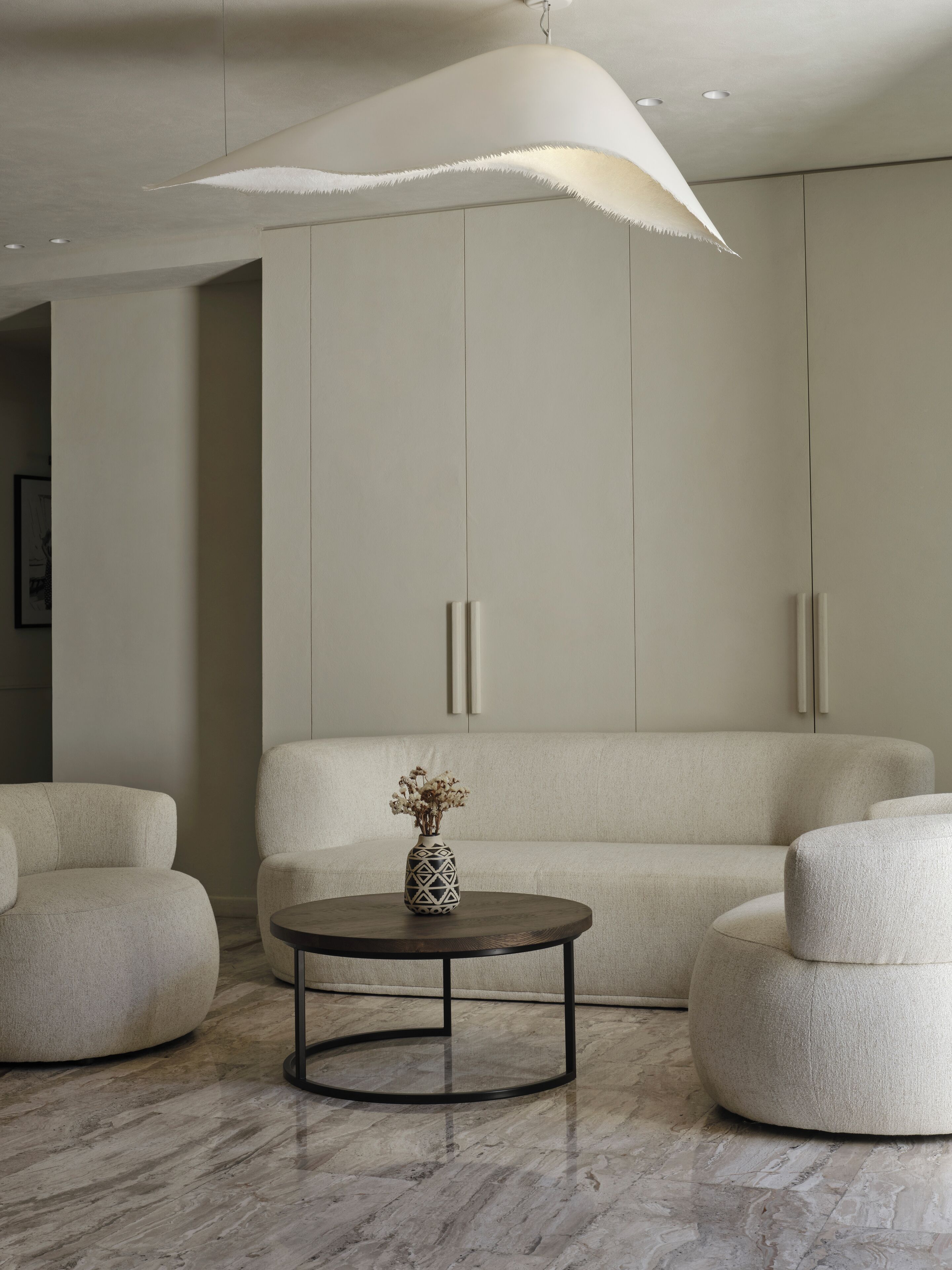 A modern living room with a round coffee table, a sofa, and a decorative vase.
