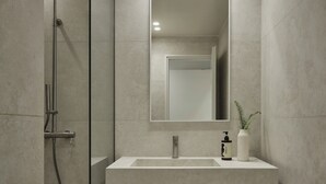 A modern bathroom with a built-in sink, a mirror, and a shower enclosure.