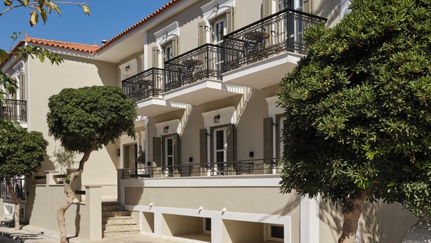 A multi-story building with balconies, a stone facade, and a tiled roof.