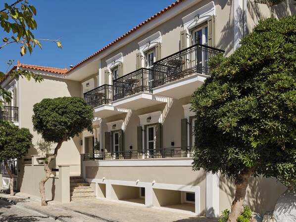 A multi-story building with balconies, a stone facade, and a tiled roof.