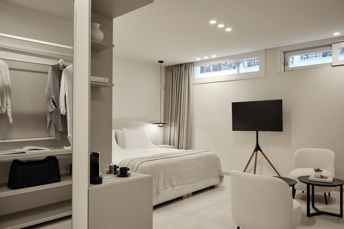 Een hotelkamer met een bed, een televisie, een bureau met stoel, en een kledingkast.