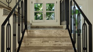 A staircase with black railings leading to a landing with a double door and windows. - Doryssa Method Hotel (Samos)