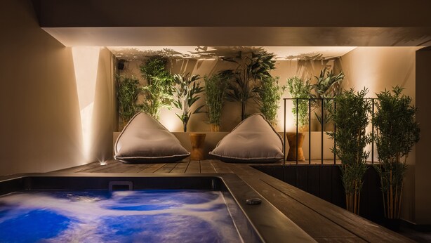 A spa area with a hot tub, wooden flooring, and potted plants. - Doryssa Method Hotel (Samos)