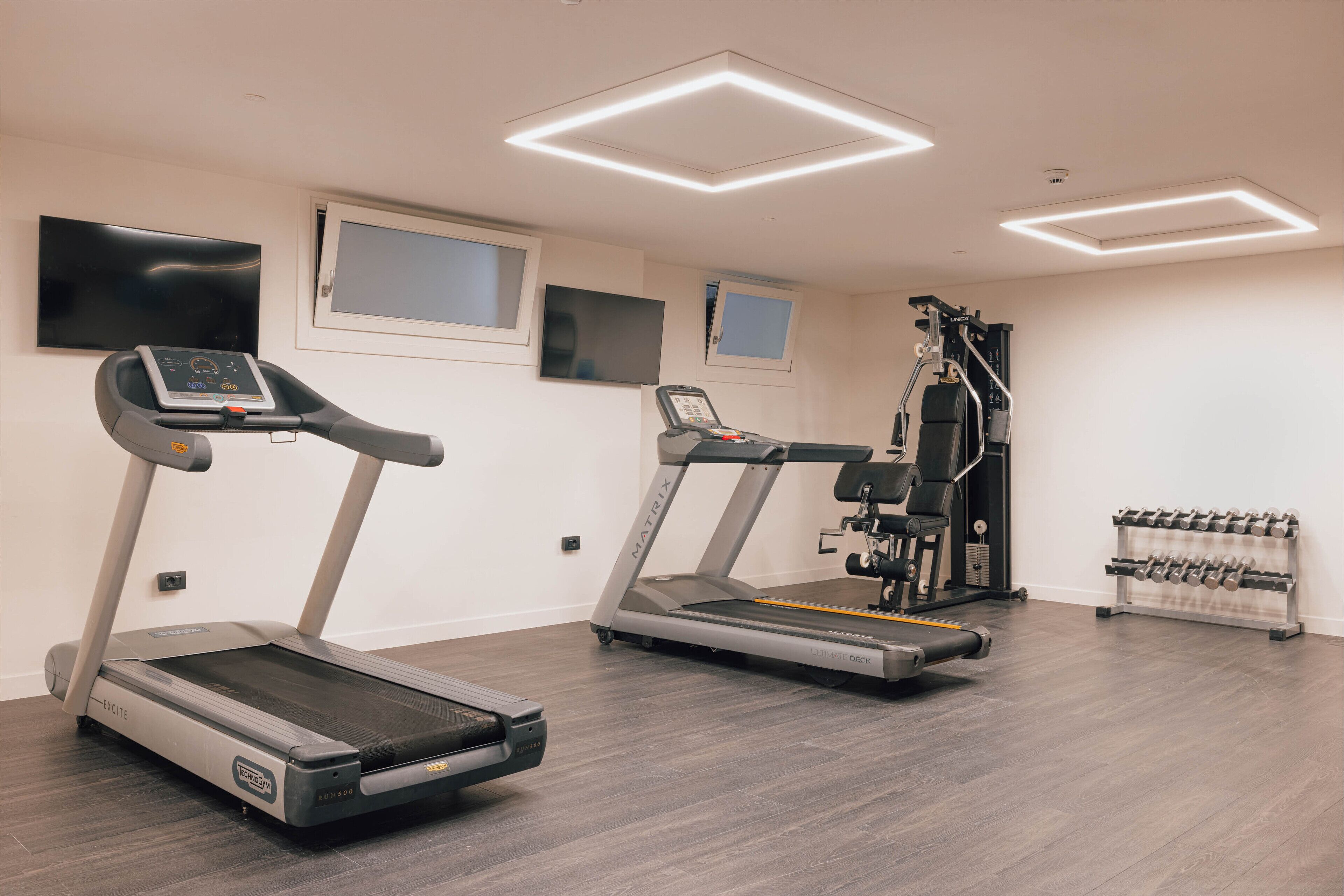 Ein modernes Fitnessstudio mit Laufbändern, Krafttrainingsgeräten und einer Kurzhantelbank.
