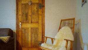 A wooden rocking chair with a fluffy cushion in a room with wooden flooring and a wooden door. - A lovingly restored old farmhouse in Heeselicht (Stolpen)