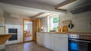 A modern kitchen with white cabinets, a built-in oven, and a dining area with a table and chairs. - A lovingly restored old farmhouse in Heeselicht (Stolpen)