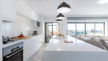 A modern kitchen with white cabinetry, a central island, and pendant lighting.