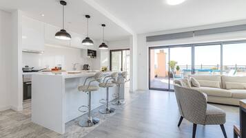 A modern kitchen with a central island, bar stools, and pendant lighting.