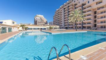 A swimming pool with a clear blue water, surrounded by a tiled deck.