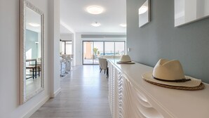 Un hall d’hôtel moderne avec un long comptoir d’accueil, un grand miroir et une vue sur la salle à manger et l’extérieur.