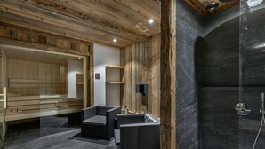 A sauna room with wooden walls, a bench, and a black tiled floor. - Luxury chalet, jacuzzi and sauna, sleeps 14. (Val-d'Isère)