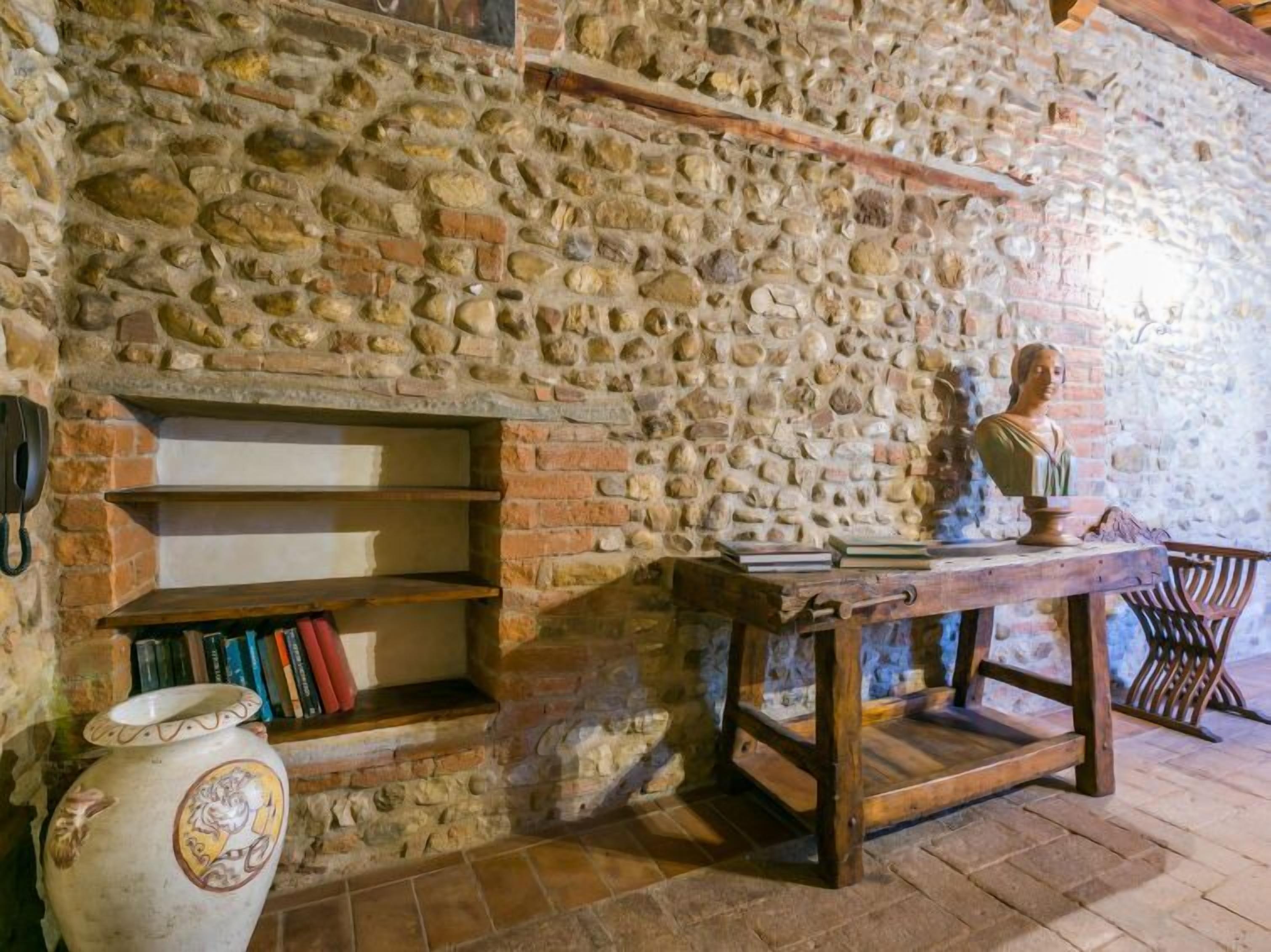 A stone wall with shelves, a bust, and a vase.