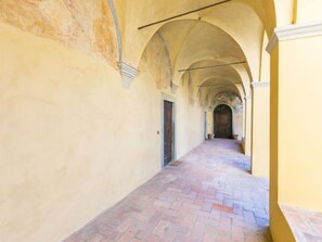 A corridor with arches and a brick floor.