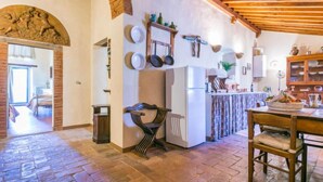 A rustic kitchen with exposed brick walls, wooden beams, and a stone floor. - Il Convento by Interhome (Montefiridolfi)