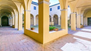 A spacious courtyard with arches, potted plants, and a brick floor. - Il Convento by Interhome (Montefiridolfi)