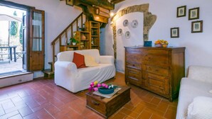 Un salon chaleureux avec un canapé blanc, un meuble en bois et un escalier menant à l’étage supérieur.