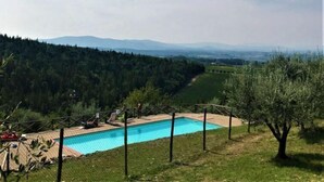 Une piscine offrant une vue sur une vallée boisée et des montagnes lointaines.