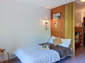 Un dormitorio con cama, mesita de noche con lámpara, cabecero de madera y un cuadro colgado en la pared.
