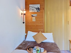 A bed with a wooden headboard, a wall-mounted light, and a framed picture. - Saint-Gervais d'en Haut by Interhome (Saint Gervais)