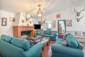 Ein Wohnzimmer mit Kamin, grünen Sofas und Geweih-Dekorationen.