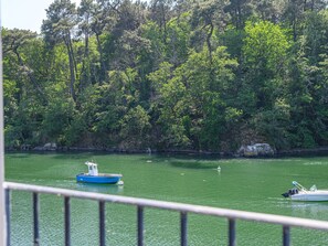 A boat on a calm river with a forested bank. - Glann Aven by Interhome (Le Bono)