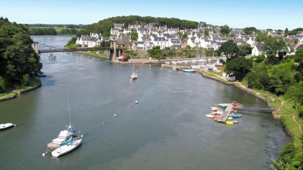 Une rivière avec des bateaux, un pont et une ville avec des maisons.