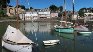 Un port où plusieurs bateaux sont amarrés, un mur de pierre et des bâtiments en arrière-plan.