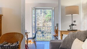 Un salon chaleureux avec un canapé, un fauteuil en osier, une table à manger et une lampe.