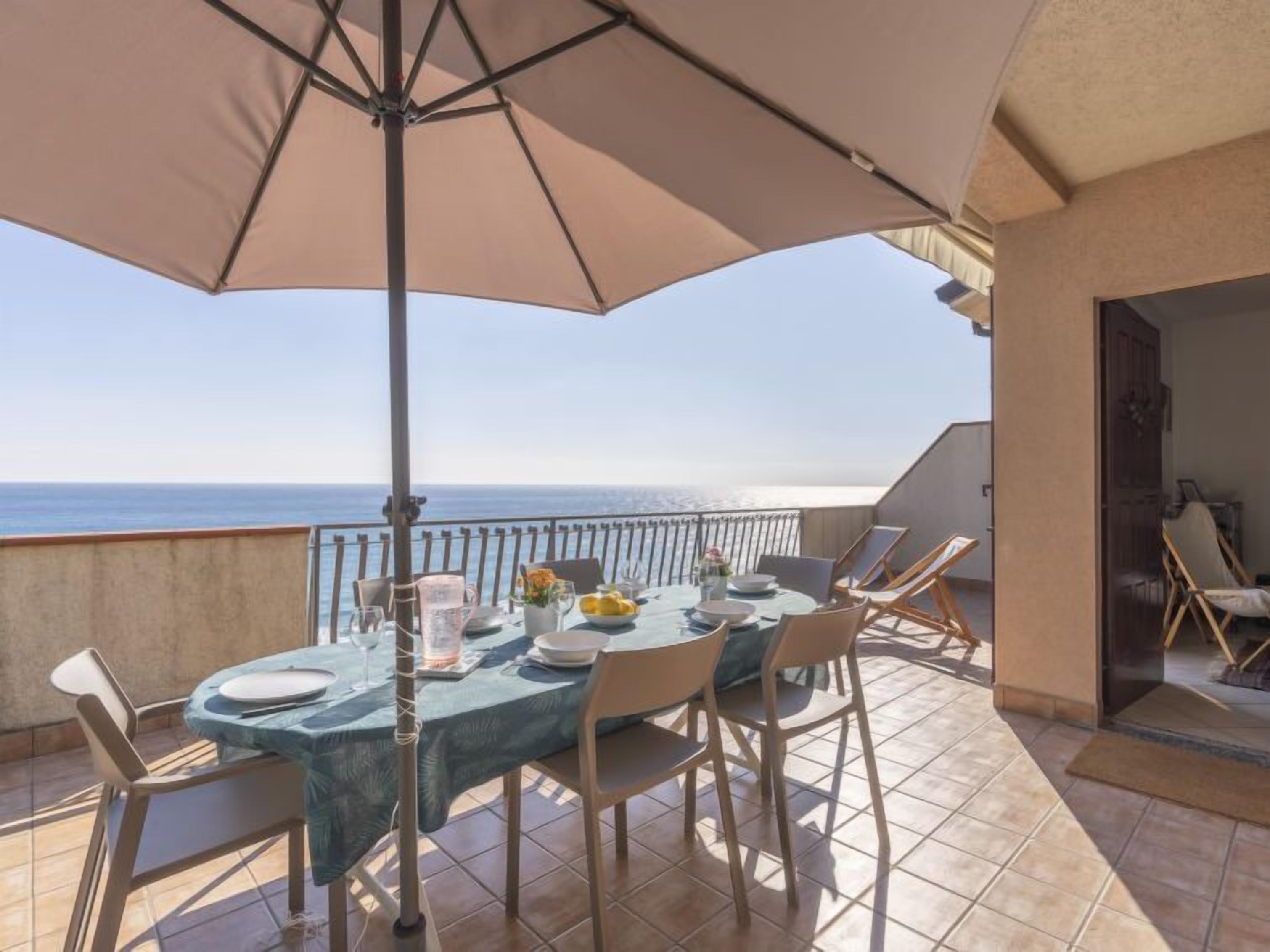 A dining area with a table set for four, overlooking the sea.