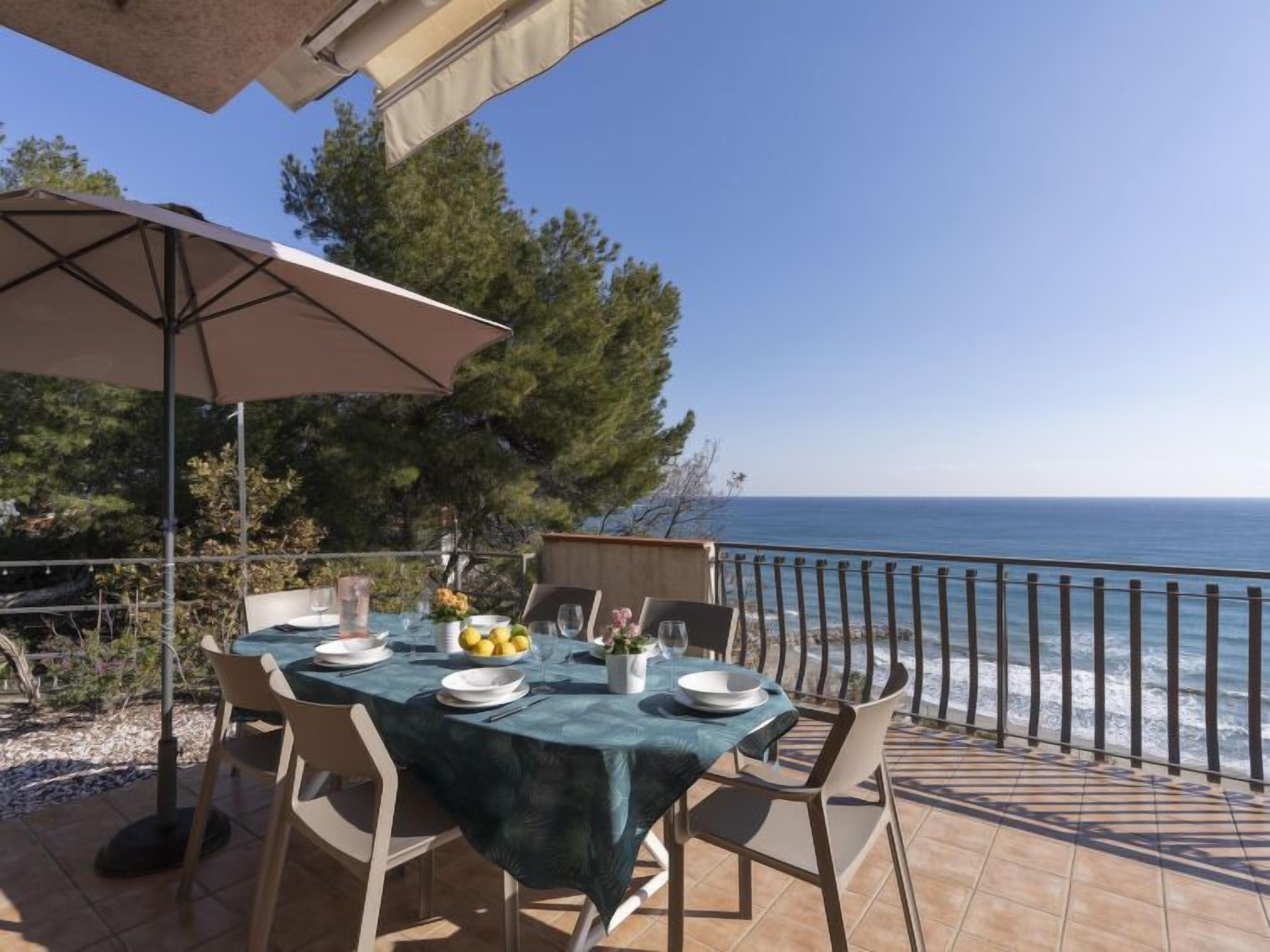 Un espace de restauration en plein air avec une table dressée pour deux personnes, offrant une vue sur la mer.