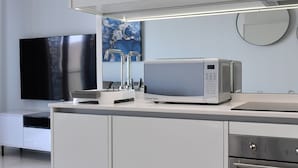 Une cuisine moderne équipée d’un four à micro-ondes encastré, d’un téléviseur à écran plat et d’une machine à café.