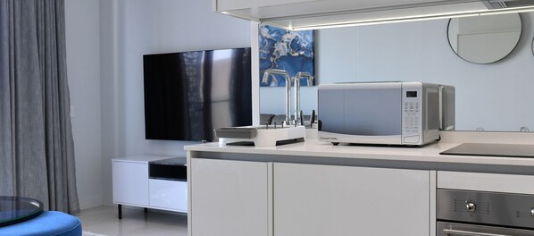 Een moderne keuken met een ingebouwde magnetron, een flatscreen televisie en een koffieapparaat.