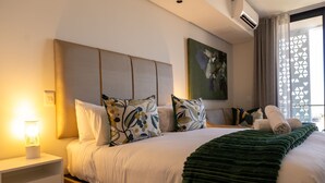 Une chambre d’hôtel avec un lit, une table de chevet, une lampe et une fenêtre avec des rideaux.