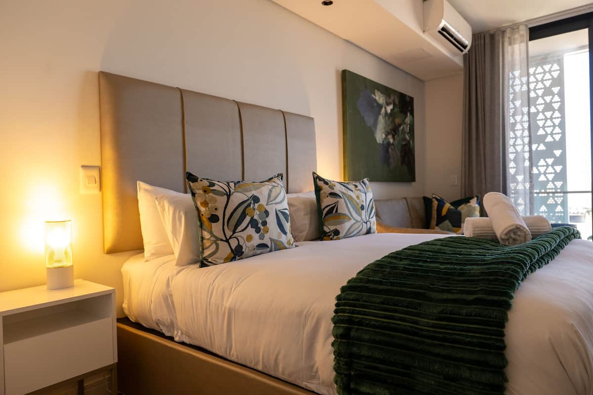 Ein Hotelzimmer mit Bett, Nachttisch, Lampe und einem Vorhangfenster.