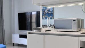 Une chambre d’hôtel moderne équipée d’une télévision à écran plat, d’un four à micro-ondes et d’un petit coin repas.