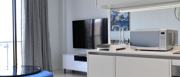 Une chambre d’hôtel moderne équipée d’une télévision à écran plat, d’un four à micro-ondes et d’un petit coin repas.